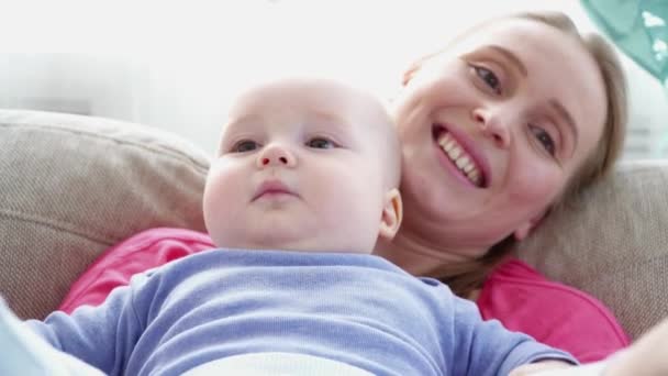 6 hónapos fia lába szóló, a kanapén Vértes játszó fiatal anya - Felvétel, videó
