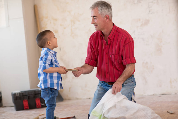 Grandsonis helping to his grandfather  in collecting old parquet - Фото, изображение