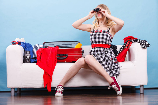 Young woman packing suitcase on couch - Фото, изображение