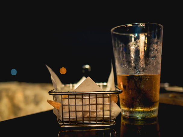 Vaso de cerveza y fritas en la mesa de la playa durante
  - Foto, Imagen