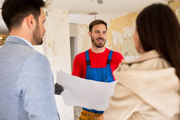Builder handyman consults with young couple about renovations th - Photo, Image
