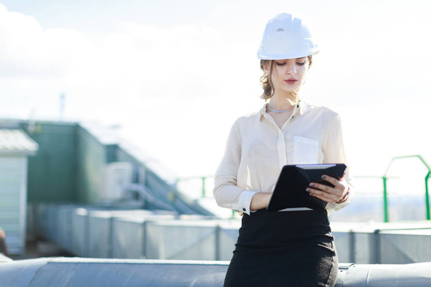 Businesswoman in helmet on the roof with tablet - Foto, Imagen