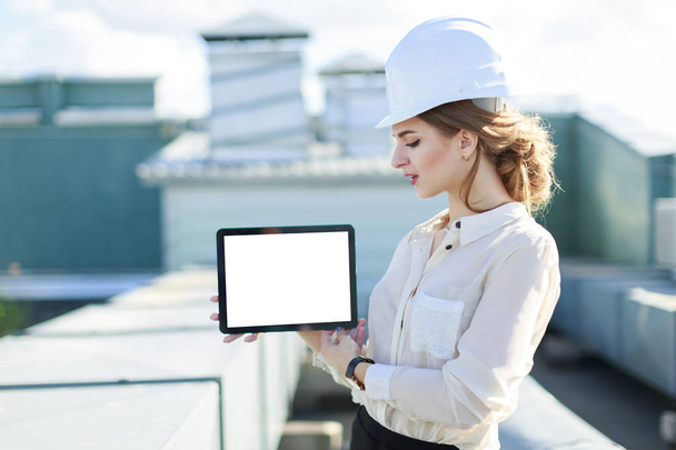 Businesswoman in helmet on the roof with tablet - Zdjęcie, obraz