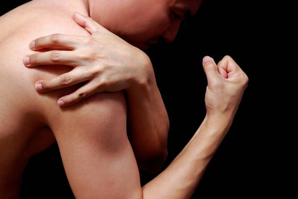asian man showing his muscle in pain, isolated on black - Fotoğraf, Görsel