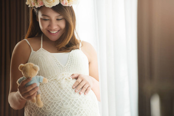 pregnant woman holding a teddy bear doll  - Фото, зображення
