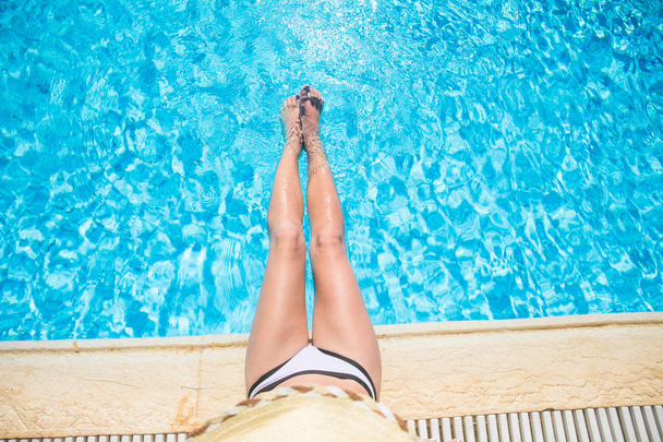 Top view young woman sunbathing near swimming pool. Top view of legs near pool - Photo, Image