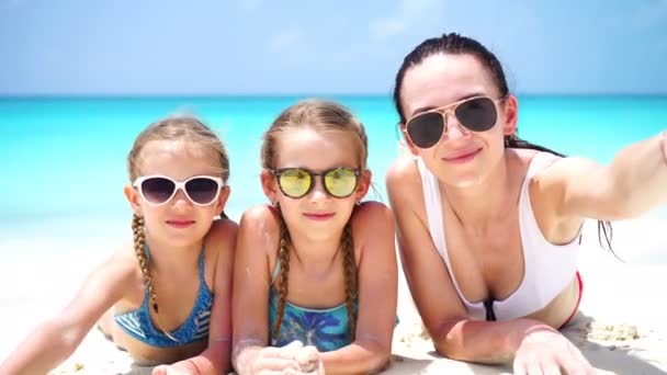 Madre y niñas tomando selfie en la playa tumbadas en arena blanca. familia feliz tomar selportrait relajarse en vacaciones
 - Metraje, vídeo