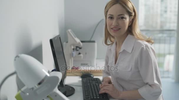 Cheerful medical professional sitting at computer - Filmati, video