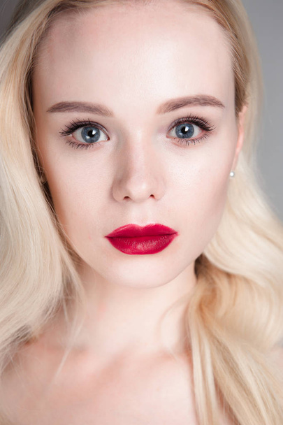 Beauty model girl with perfect make-up red lips and blue eyes looking at camera. Portrait of attractive young woman with blond hair. Beautiful female face with clear fresh skin. Fashion close up shot. - Foto, Imagen