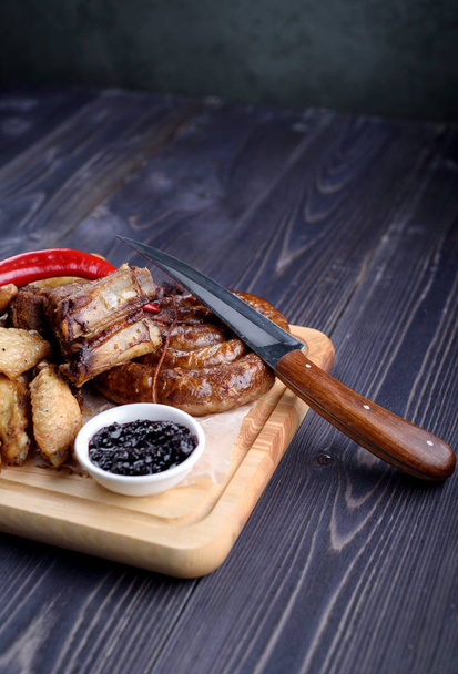 Grilled sausages and chicken with fries on a wooden board - Foto, afbeelding