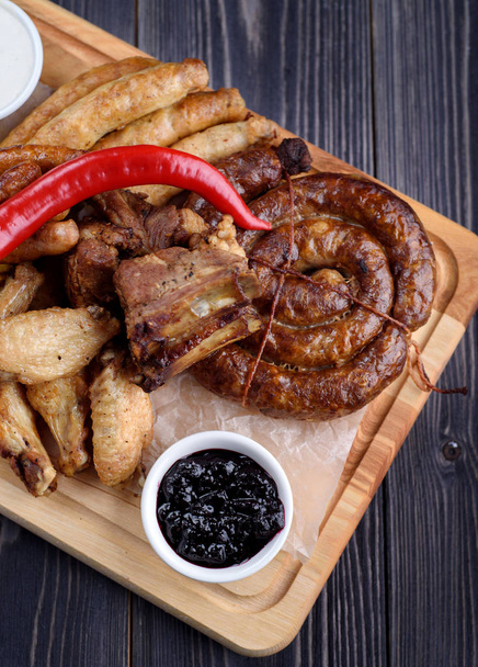 Grilled sausages and chicken with fries on a wooden board - Fotoğraf, Görsel