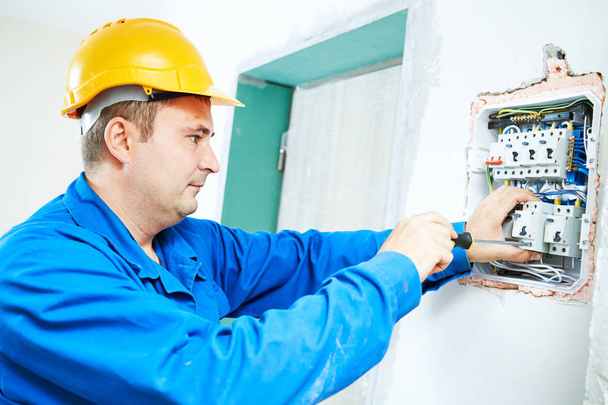 electrician installing switching electric actuator in fuse box - 写真・画像