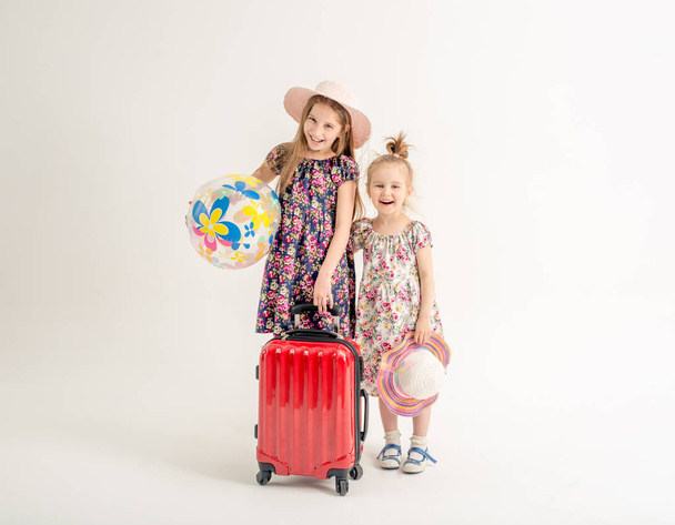 Happy sisters stand near a suitcase - Fotó, kép