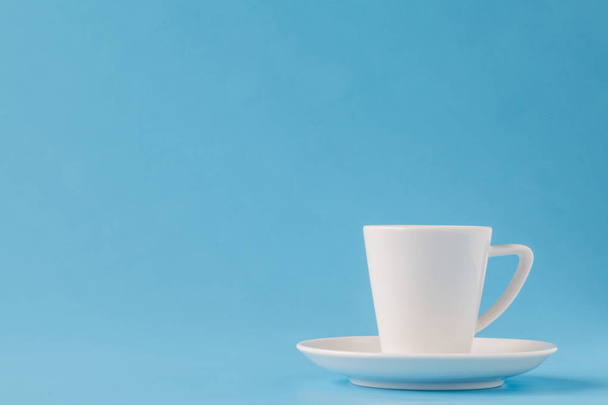 modern stylish white coffee cup or mug on a plate on a blue back - Foto, imagen