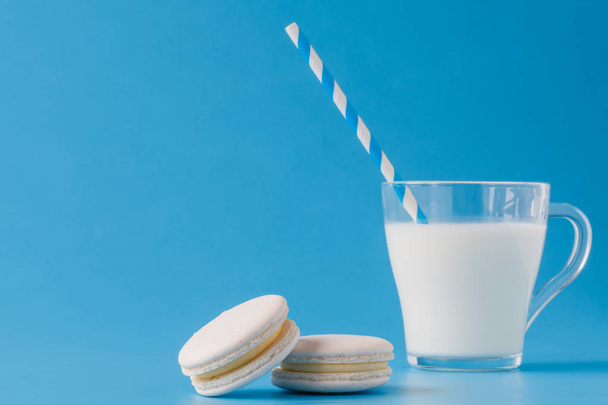 Glass of milk with french macaroon on blue background with copy  - Fotoğraf, Görsel