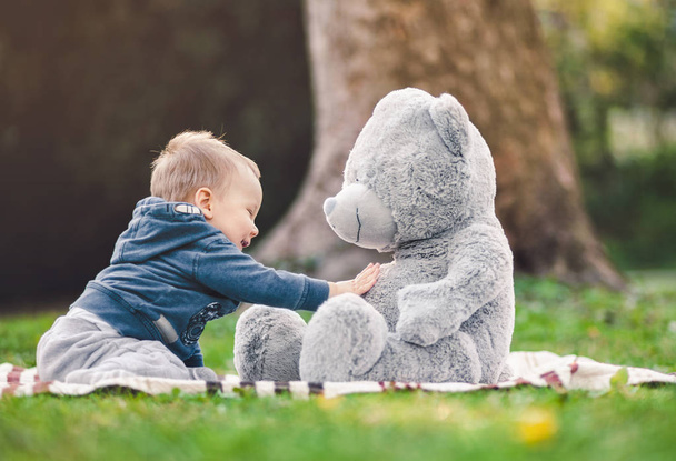 Best of friends. Cute toddler playing outdoors with his teddy bear  - Photo, image