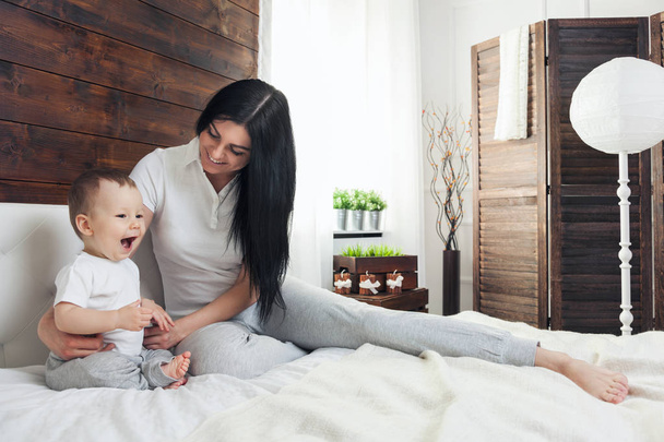 Happy mother with her cute child on the bed having a good time - Foto, Bild