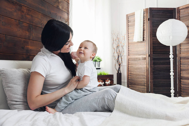 Happy mother with her cute child on the bed having a good time - Фото, зображення