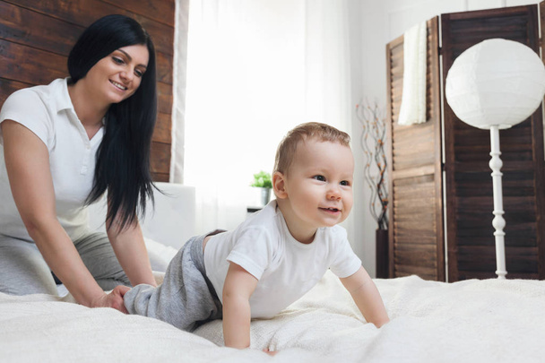 Happy mother with her cute child on the bed having a good time - Foto, immagini