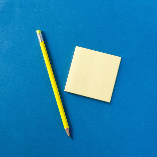 neongelber Bleistift und Notizblock auf blauem Hintergrund, Draufsicht - Foto, Bild