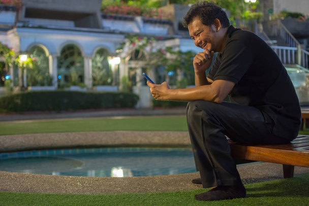 Mann lacht am Pool mit Smartphone - Foto, Bild