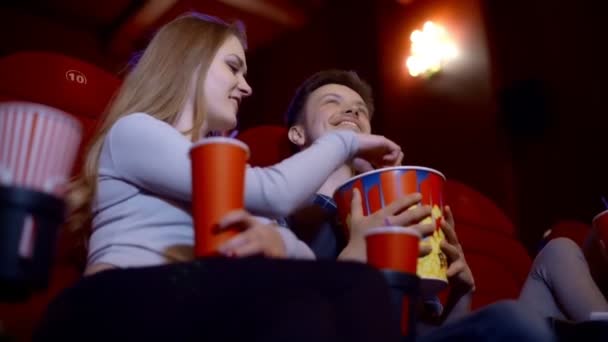 Gelukkige paar zitten in de bioscoop, kijken naar film, eten popcorn, glimlachend. - Video