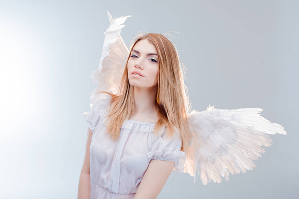 An angel from heaven. Young, wonderful blonde girl in the image of an angel with white wings. - Photo, Image
