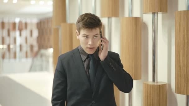 Handsome businessman making a phone call with smartphone in the trade center - Кадры, видео