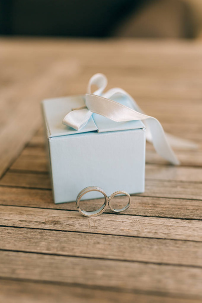 Anelli nuziali su una texture di legno chiaro in una scatola blu. Matrimonio j
 - Foto, immagini