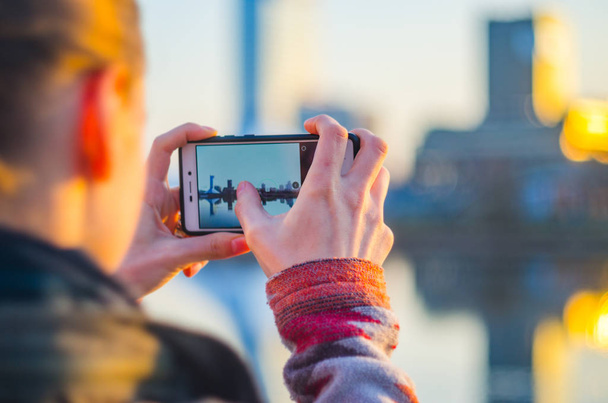 Young woman takes pictures of the city on a smartphone - Foto, imagen