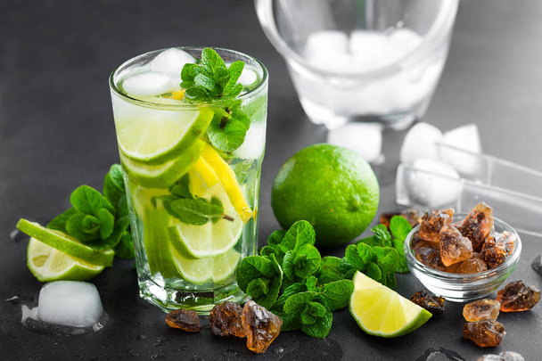 Refreshing mint cocktail mojito with rum and lime, cold drink or beverage with ice on black background - 写真・画像