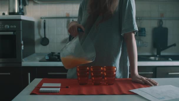 tollpatschige brünette Frau gießt Orangensaft in rotes Glas und verschüttet es überall - Filmmaterial, Video