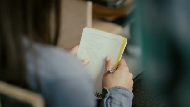 Close-up view of female hands. Woman sitting on a chair and writing in notebook. Student talking with people at lecture. - Filmati, video