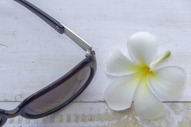 Closeup flower with sunglasses on white wooden background. - Photo, Image