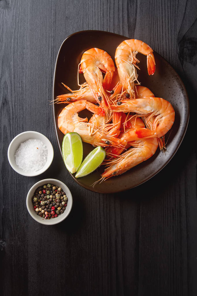 Fresh raw shrimps, lime in a bowl on a wooden table. Eating seaf - Foto, Imagen