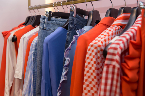 Різний одяг на вішалках крупним планом в магазині
 - Фото, зображення