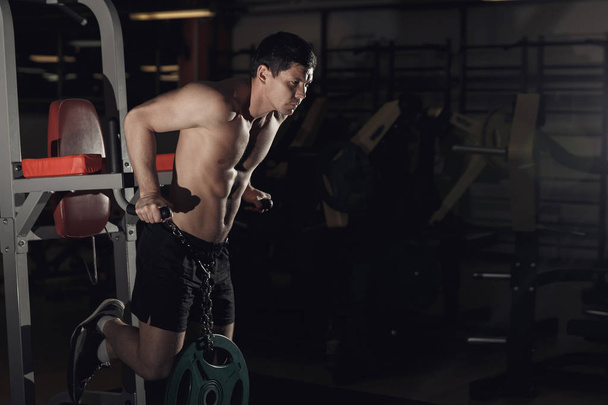 Gespierde bodybuilder trainen in de sportschool doen oefeningen op paral - Foto, afbeelding