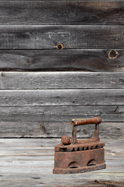 Le vieux fer à charbon lourd et rouillé repose sur une surface en bois
 - Photo, image