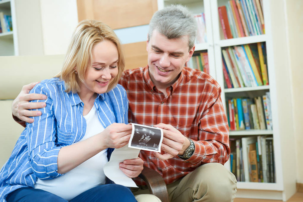 Happy couple at home discussing ultrasound scan image - 写真・画像
