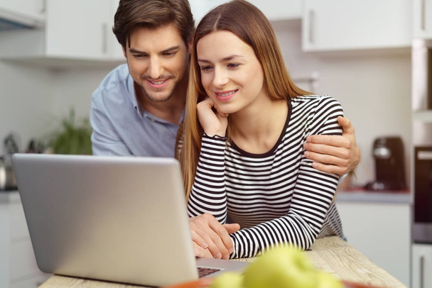 Young couple using a laptop in the kitchen - Foto, afbeelding