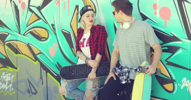 Trendy modern urban couple chatting at skate park - Footage, Video