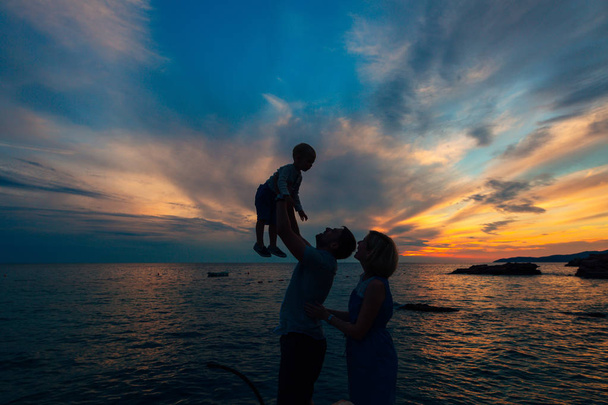 Silhouette of parents with a child at sea. Family on the beach i - Photo, Image