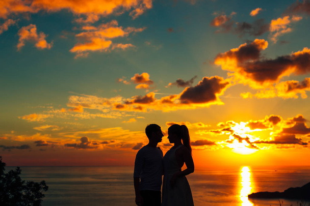 Hiljattain avioituneen parin siluetti merellä auringonlaskun aikaan. Häät sisään
 - Valokuva, kuva