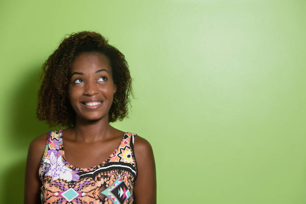 African american vrouw zijwaarts op zoek naar een groene muur - Foto, afbeelding