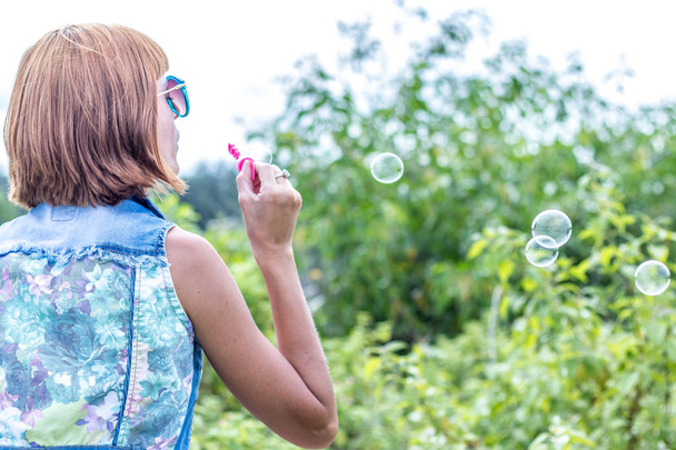 Beautiful young woman blowing bubble in outdoor, nature, near the ocean. Tropical magic island Bali, Indonesia. - Фото, изображение