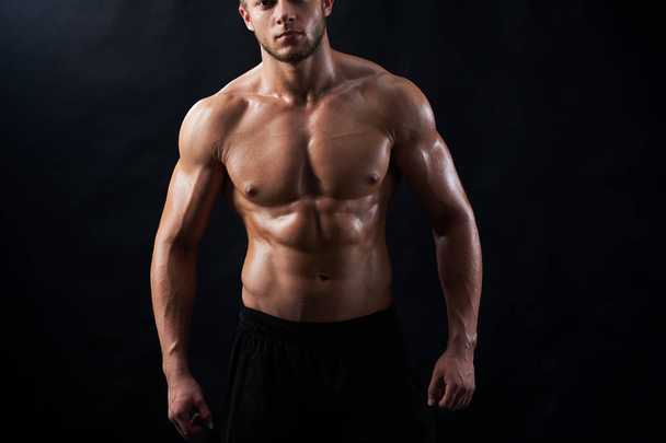 Young muscular fit sportsman posing shirtless on black backgroun - 写真・画像