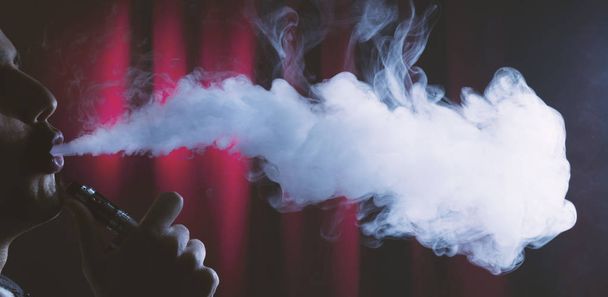 holding electronic cigarette or e cig and vaping clouds. - Foto, Imagen