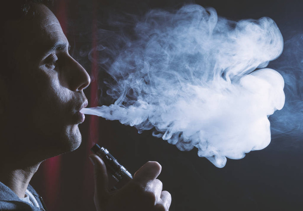 Młody człowiek posiadający elektroniczny papieros lub e cig i vaping cl - Zdjęcie, obraz