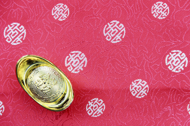 Chinese goudstaaf op fragment van rode chinese zijde voor pagina - Foto, afbeelding