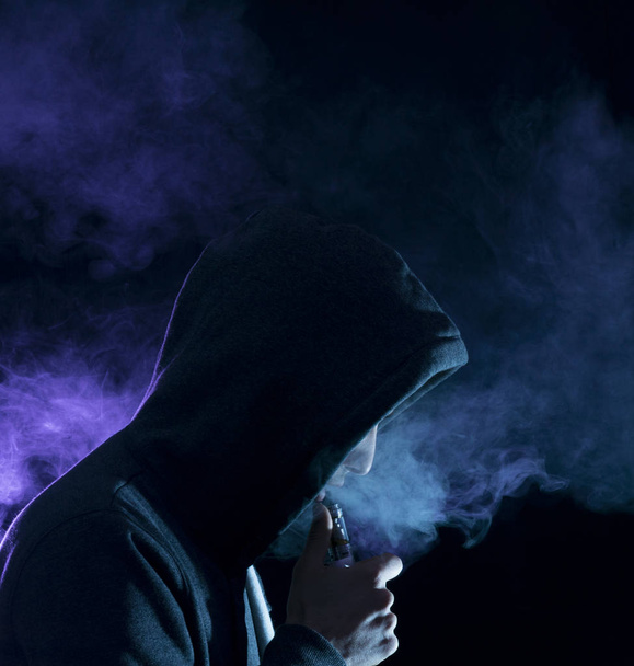 мужчина испарил электронную сигарету большим количеством дыма
.  - Фото, изображение